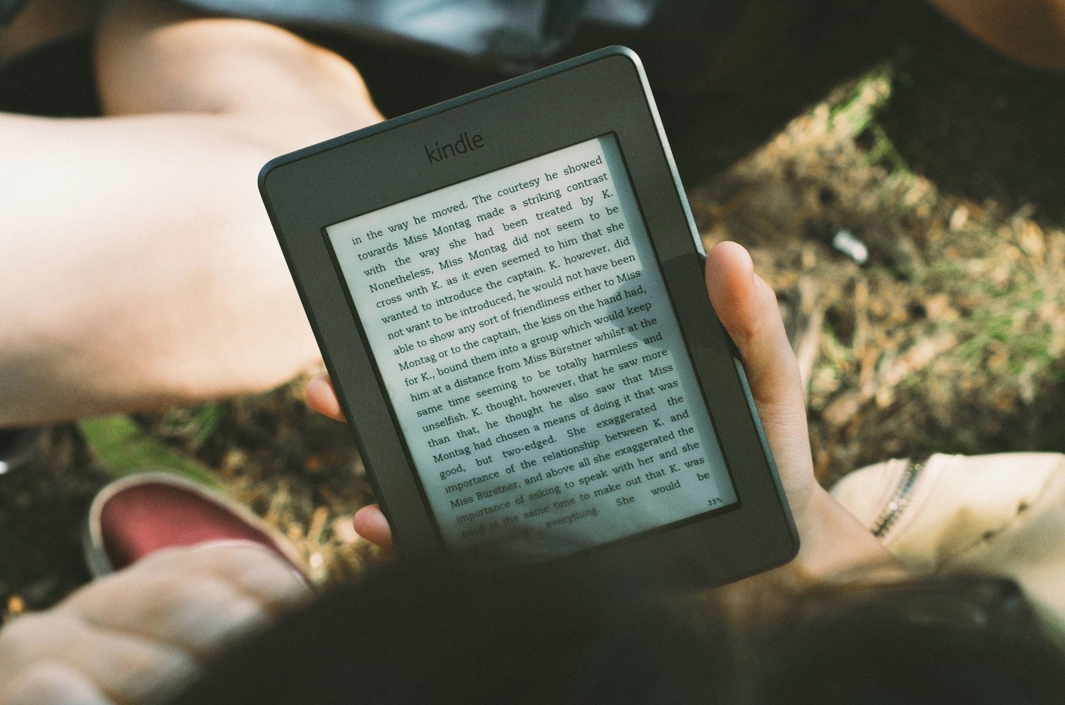 Hands holding a Kindle e-reader outdoors